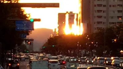 ビルの間に沈む夕日と車の列